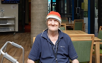 A man sits at a table smiling at the camera.